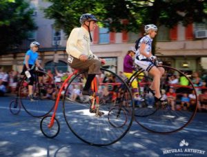 Two people on high-wheel bikes racing in the National Clustered Spires High Wheel Race