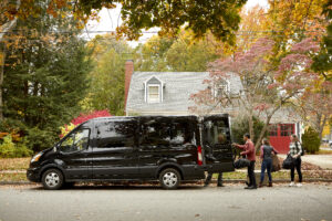 Sideview of landbird van with trunk open and people taking luggage out