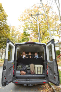 A family in the back of the van with trunk doors open and luggage inside