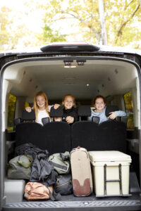 Landbird passengers in the back seat looking out at an open trunk with gear in it